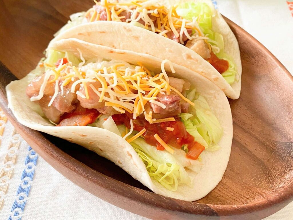 木製の器にのせられたチキンタコス2つ