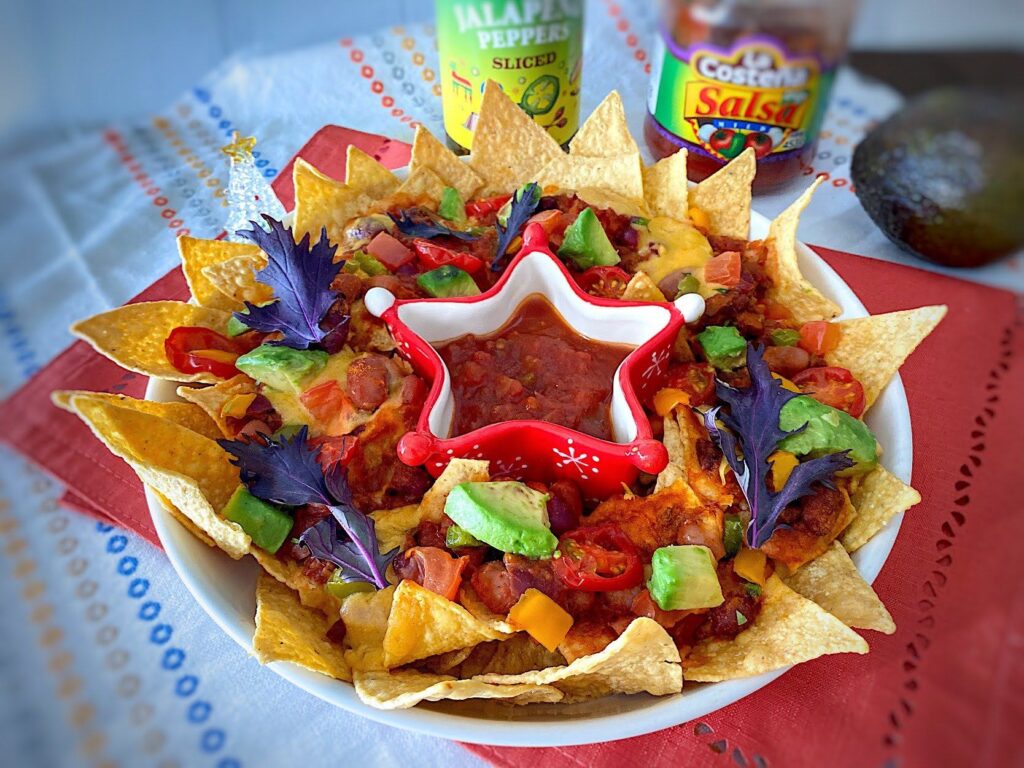 クリスマスカラーのナチョチップス。真ん中にサルサ、トッピングにアボカドやチーズなどがのっている。